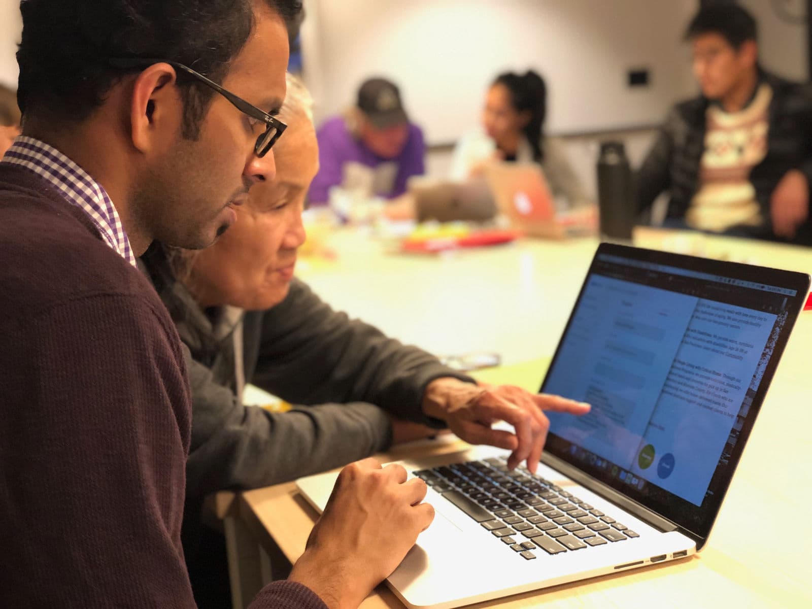 A volunteer and community representative reviewing the SF Service Guide at a Datathon